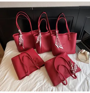 Detail view of red lychee grain leather tote bags with elegant scarves and floral charms