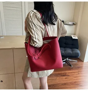 Detail of red leather tote bag with floral charm decoration and large capacity