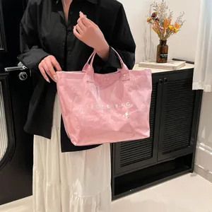 Sac fourre-tout rose imperméable avec imprimé TOTE BAG blanc porté par un mannequin