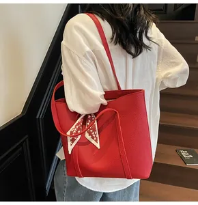 Macro detail of red lychee grain leather tote bag with decorative patterned silk scarf handle
