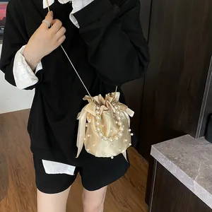 Elegante borsa a secchiello in raso champagne con manici di perle e catena dorata