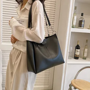 Minimalist black PU leather tote bag with chain strap shown on model in modern room