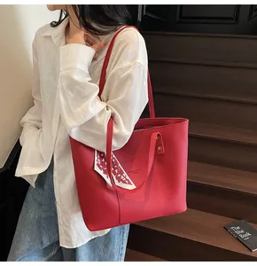 Detail of red pebbled leather tote bag with elegant silk scarf and logo engraving