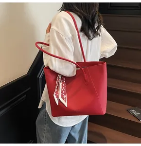 Detail of red pebbled leather tote bag with silk scarf and logo on outdoor stairs