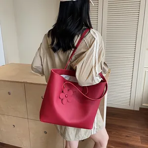 Red pebbled leather tote bag with floral charm and spacious interior for daily use