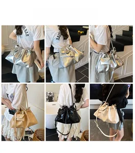 Detail of a metallic glossy drawstring bucket bag with adjustable strap and side pocket