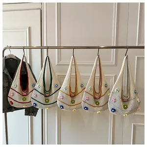 Détail de cinq sacs hobo en crochet à fleurs colorées suspendus à un support métallique