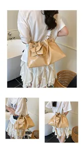 Detail of beige drawstring bucket bag with glossy crinkled leather texture and mini pouch