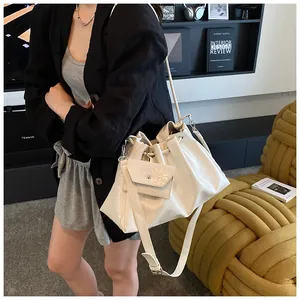Detail of off-white drawstring bucket bag with mini envelope pouch and sleek leather strap