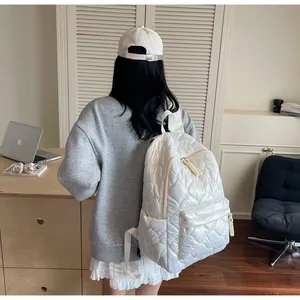 Rear view of a white quilted puffer backpack showing side pocket and woven handle detail