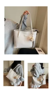 Gros plan du sac cabas crème minimaliste avec texture cuir et charm d'ours