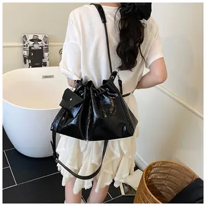 Detailed view of a black glossy drawstring bucket bag with a small matching coin purse