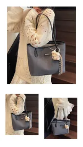 Détail du sac cabas gris foncé avec pendentif ours sur un escalier en bois