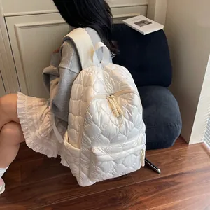 Quilted white puffer backpack with large diamond stitching shown on model in minimalist room