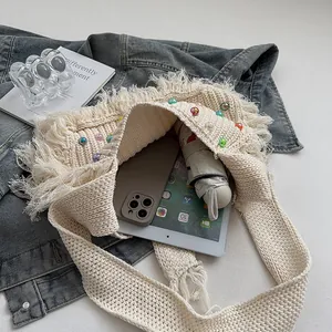 Handmade crochet fringe tote bag in cream with beads, holding a tablet and umbrella
