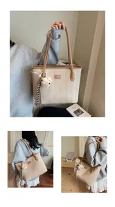 Détail du sac cabas en toile beige avec bordure en cuir marron et pendentif ours