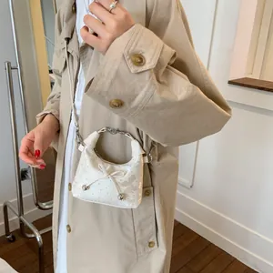 Mini sac seau blanc avec nœud et imprimé papillon porté par un mannequin en trench-coat