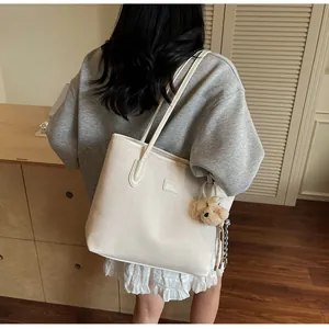 Détail du sac cabas crème avec texture à chevrons et breloque chien en peluche