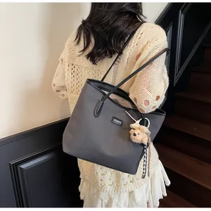 Détail du sac cabas gris texturé avec logo et breloque ours en perles