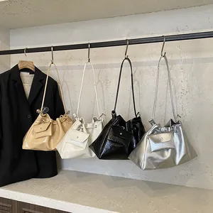 Minimalist drawstring bucket bag in four glossy colors displayed on a metal rack