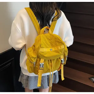 On-body shot of a yellow nylon backpack with flap closure and silver metal buckle