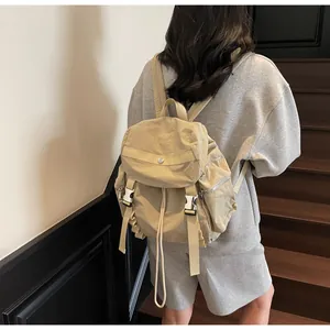 Lightweight khaki nylon backpack with buckle flap and multiple pockets on female model