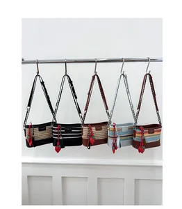 Detail of woven bucket bags in various colors with leather straps and strawberry charms
