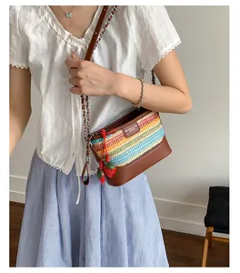 Detail of colorful woven straw bucket bag with red strawberry charms and leather strap