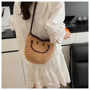 Gros plan d'un sac seau en paille avec un motif smiley marron et une longue bandoulière