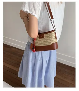Detail of woven straw bucket bag with brown leather trim and red chili charm