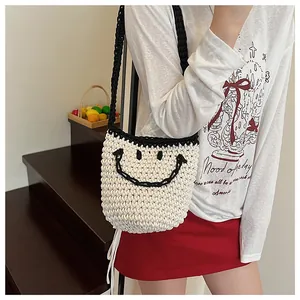 Détail d'un sac à bandoulière en paille tissé à la main avec smiley noir et forme de seau