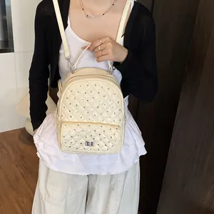 Mini sac à dos crème matelassé avec strass et fermoir rotatif argenté porté par un mannequin