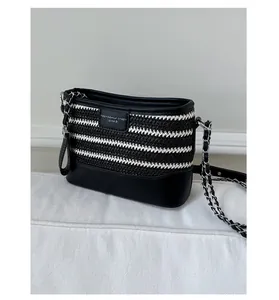 Detail of black and white striped woven tote with leather trim and gold chain strap
