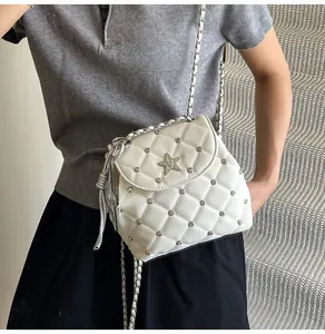 Detail of white quilted crossbody bag with star rhinestone and silver rivets