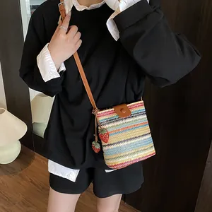 Handwoven multi-color striped straw bucket bag with leather flap and strawberry charms