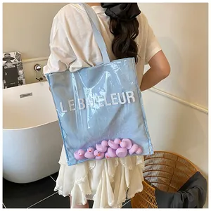 Détail du sac cabas transparent avec canards en caoutchouc mauves et imprimé de lettres