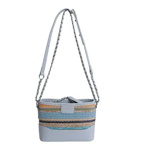 Light blue leather bucket bag with colorful woven rainbow stripes and chain strap