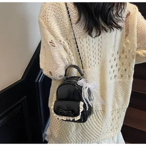 Detail of black patent leather bucket bag with lace edges and elegant pearl chain