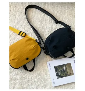 Détails des sacs coquille jaune moutarde et noir avec bandoulières sur tapis blanc