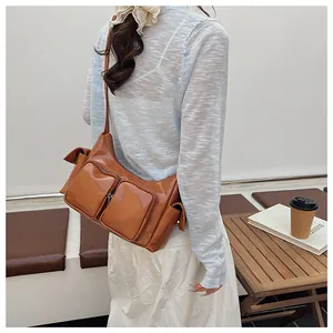 Detailed view of caramel brown multi-pocket shoulder bag on a model in outdoor setting