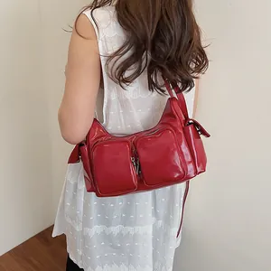 Fashionable red patent leather shoulder bag with multi-pocket design on white background