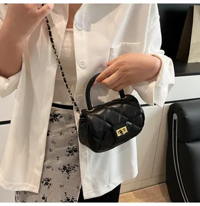 Detail of black quilted leather mini bag with gold twist lock and chain strap