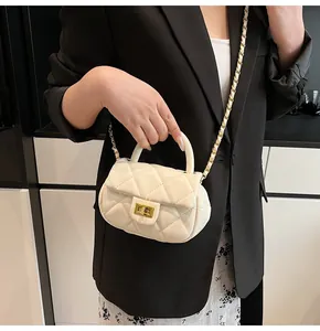 Detail of cream quilted crossbody bag featuring a gold twist lock and metal chain strap