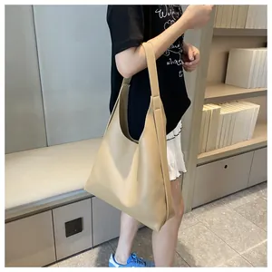 Minimalist khaki tote bag detail showing large capacity and smooth leather texture on model