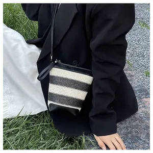 Fashionable black and white woven striped crossbody bucket bag shown on a model outdoors