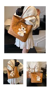 Detail of a large brown tote bag with bear print and a cute plush bear charm