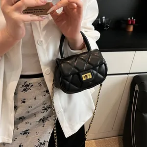 Elegant black quilted crossbody bag with golden clasp and chain strap held by model