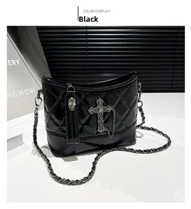 Detail of black quilted leather shoulder bag with gothic silver cross and skull charms
