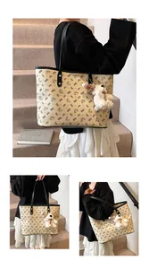 Detail of beige tote bag with bear print featuring black straps and plush charm on stairs