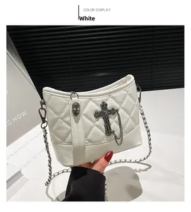 Close-up of white quilted shoulder bag with metal cross chain and skull decoration